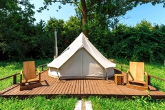 Tent with wooden chairs in front of it at glamping